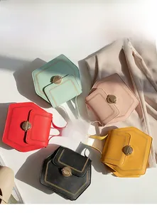 Top view of five hexagonal crossbody bags in various colors with metallic clasp