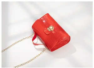 Detail of red crocodile pattern handbag with golden metal lock and chain strap