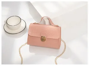 Detail of pink crocodile embossed handbag with golden twist lock and chain strap