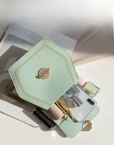 Mint green small flap bag with hexagon lock and stitching showing interior capacity