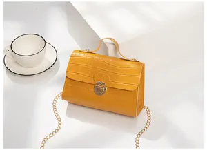 Close-up of yellow crocodile pattern handbag with elegant gold metal twist lock and chain
