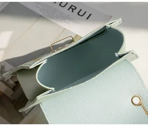 Detail view of mint green faux leather handbag with hexagonal clasp and gold chain strap