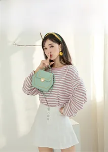 Detail of mint green hexagonal crossbody bag with gold lock and decorative stitching