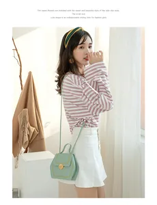 Detail of mint green hexagonal crossbody bag with contrast stitching and gold lock