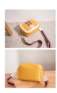 Detailed close-up of yellow pebbled leather camera bag with striped ribbon strap