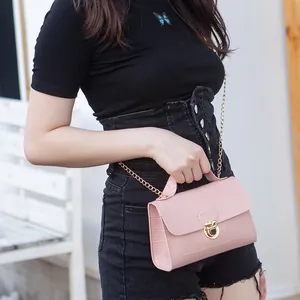 Pink crocodile pattern shoulder bag with gold hardware worn by model in casual outfit