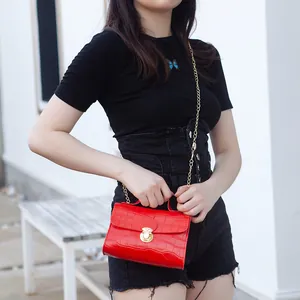 Red crocodile pattern mini crossbody bag with gold chain strap and top handle on model