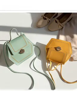 Close-up of hexagonal crossbody bag with vintage circular metal lock and stitching details