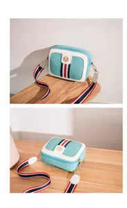 Detail of mint green camera bag with striped ribbon decoration and golden metal hardware