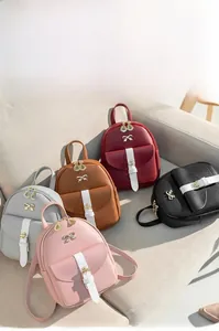 Collection of mini faux leather backpacks in five colors displayed on a beige sofa