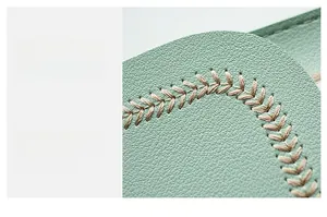 Macro view of light green leather bag showing fine cross-stitch and pebble texture