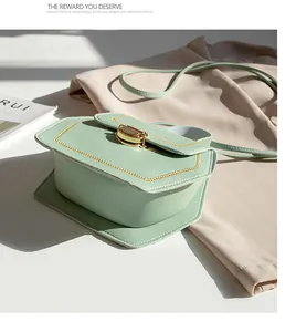 Detail of mint green crossbody bag featuring gold hexagonal lock and contrast stitching