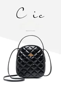 Close-up of black quilted leather backpack with golden bee metal logo and diamond pattern