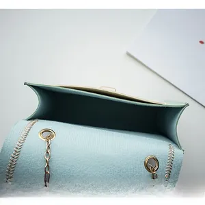 Close-up of the light blue crossbody bag interior with gold chain and woven seam details