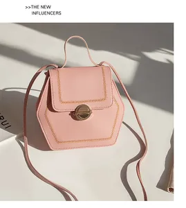 Detail of light pink hexagonal crossbody bag with golden stitching and metal lock