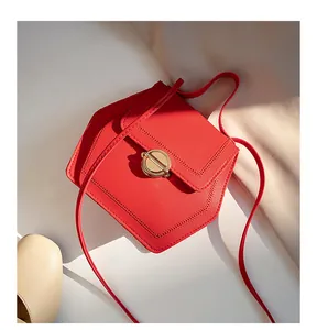 Close-up of a red hexagonal crossbody bag with matte leather and a gold circular lock