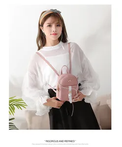 Detail of a pink mini backpack featuring a gold bow accent and white strap buckle