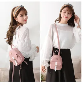 Detail view of pink mini backpack with golden bow and white straps in dual-use style