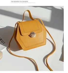 Detail of yellow hexagonal leather handbag with a gold rotary lock and stitching accents