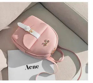 Detail of pink mini backpack featuring golden bow buckle and smooth leather texture