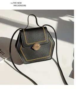 Close-up of hexagonal crossbody bag with golden embroidery and metal twist lock