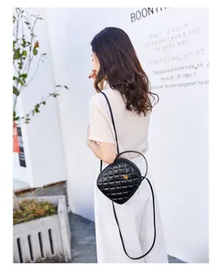 Outdoor street style view of a black quilted crossbody bag with a golden bee metal logo