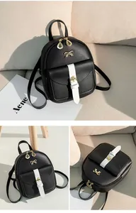Detail of mini black pebbled backpack with contrast white buckle and gold bow detail