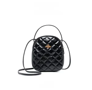 Detail of black quilted leather mini bag with gold bee charm and glossy finish