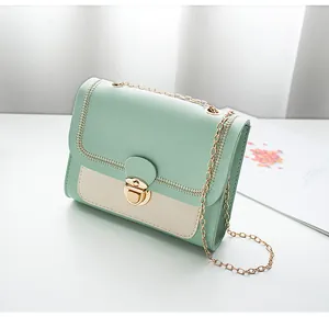Detail of mint green and cream crossbody bag with gold lock and sawtooth stitching
