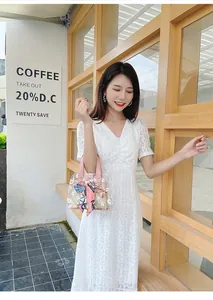 Détail d'un sac seau transparent en PVC avec poignée en soie fleurie et pochette paille
