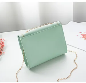 Detail of mint green chain bag with golden chevron embroidery and metallic strap
