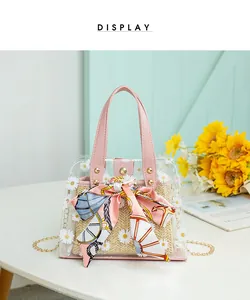 Détail du sac seau transparent à fleurs avec foulard rose et finitions dorées chic