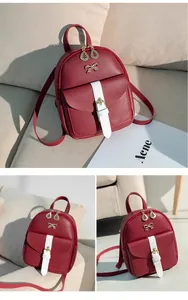Detail of burgundy mini backpack featuring gold bow accent and white buckle strap