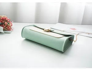 Detail view of the mint green and cream leather bag featuring a gold twist lock and chain
