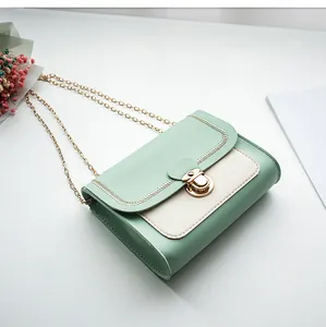 Detail of mint green and cream crossbody bag with golden chain and wave stitching
