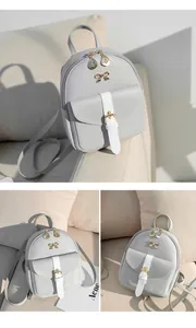 Detail view of mini grey backpack featuring white strap buckle and golden bow accent