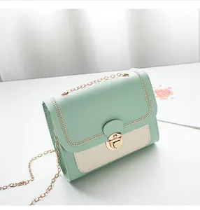 Close-up of mint green and beige contrast bag with gold chain and metal lock detail