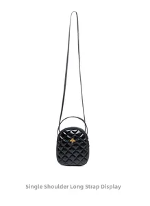 Detail of black quilted shoulder bag featuring gold bee hardware and long strap