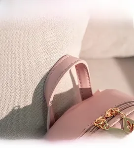 Detail of light pink backpack showing golden leaf-shaped zippers and leather handle