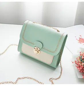 Detail of mint green and cream crossbody bag with gold metal lock and fine stitching