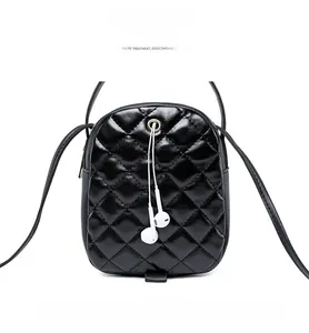 Detail of black quilted leather crossbody bag featuring a metal headphone jack and strap