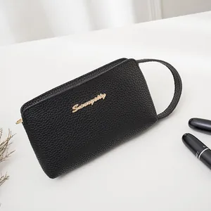Elegant black pebbled leather wristlet clutch with golden logo and zipper detail