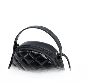 Detail of black quilted round bag featuring golden metal logo and ring top handle