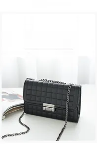 Détail d'un sac à bandoulière matelassé noir avec chaîne argentée et fermoir en métal
