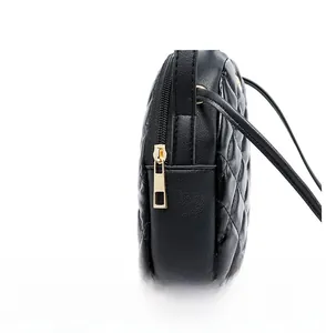 Detail of smooth gold metal zipper and quilted black faux leather on small bag