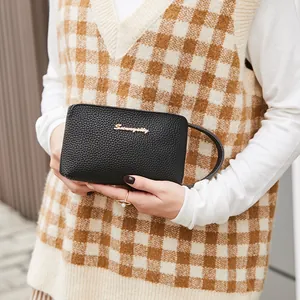 Chic black litchi pattern leather clutch bag with golden logo held by a hand