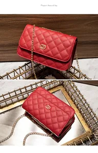 Detail van een rode gewatteerde leren tas met gouden ringen en een elegante kettingriem