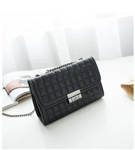 Détail d'un sac bandoulière matelassé noir avec fermoir métallique à anneaux et chaîne dorée