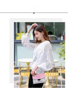 Outdoor street style view of a pink plaid crossbody bag with metal ring lock detail