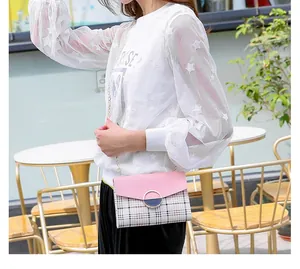 Detail of a pink crossbody chain bag with plaid pattern and a blue circular buckle